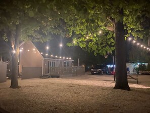 A small building with a porch, surrounded by trees and string lights. - Costa Wasaga Cottage 1 (Wasaga Beach)