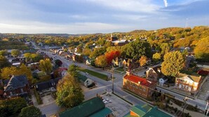 Une ville où se côtoient des immeubles résidentiels et des bâtiments commerciaux, une église imposante et d’où l’on peut admirer une vue dégagée sur les collines environnantes.