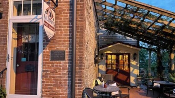 Un bâtiment en briques avec une enseigne sur laquelle on peut lire « MUNHART’S ». Il y a des tables et des chaises à l  ’extérieur, ainsi qu’un patio couvert.