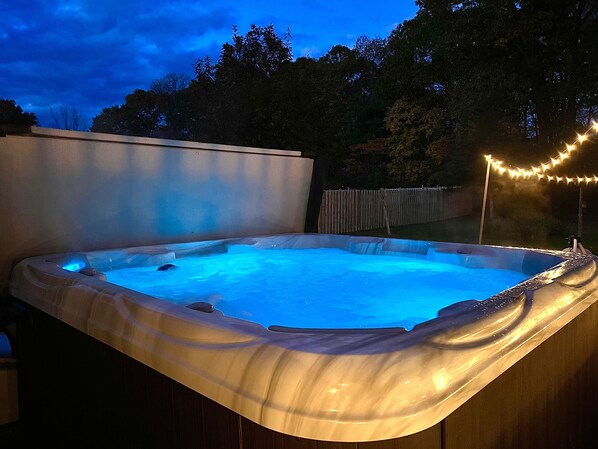 Ein Whirlpool in einem Garten mit Holzterrasse und Lichterkette.
