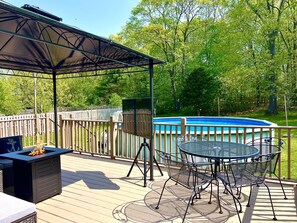 Eine überdachte Terrasse im Freien mit Pool, Feuerstelle und Gartenmöbeln.