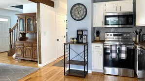 Una cocina moderna con armarios blancos, electrodomésticos de acero inoxidable y una escalera de madera.