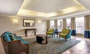 Relax in a spacious room with a comfortable seating area, large mirror, and floor-to-ceiling windows offering a view of the outside.