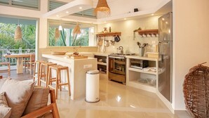 Une cuisine moderne dotée d’un îlot central, d’appareils électroménagers en acier inoxydable et offrant une vue sur un paysage verdoyant.