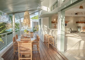A wooden deck with a dining table and chairs, a hanging light fixture, and a view of the ocean. - Tropical Penthouse in the Heart of Last Terrenas (Las Terrenas)