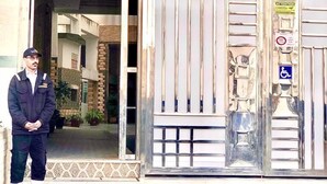 A building entrance with a glass door, a wheelchair accessibility sign, and a person standing outside. - Appartement Spacieux et Ensoleillé Plein sud Avec Grande Terasse Sans vis a vis (Tangier)