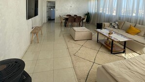 A modern living room with a sofa, a coffee table, and a dining area with chairs. - Appartement Spacieux et Ensoleillé Plein sud Avec Grande Terasse Sans vis a vis (Tangier)