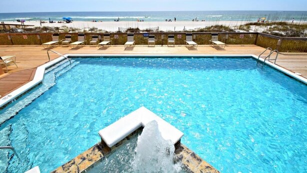A pool with a wooden deck and a view of the beach. - Broadmoor 503 Steps to the beach! Come make lasting memories! (Orange Beach)