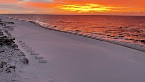 A beach with a sunset, sandy shore, and a wooden walkway. - Broadmoor 503 Steps to the beach! Come make lasting memories! (Orange Beach)