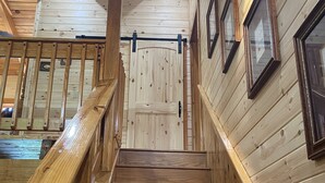 A wooden staircase with a handrail, leading to a door with a light fixture above it. - New Hot Tub, Outdoor Bar, Family Friendly, Awesome Views, Golf, Bears, Pool (Gatlinburg)