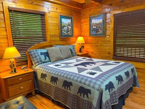 A cozy wooden cabin bedroom with a bed, two nightstands, a lamp, and a clock.