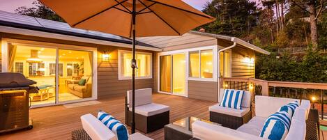 An outdoor deck with wicker furniture, a barbecue grill, and a large umbrella.