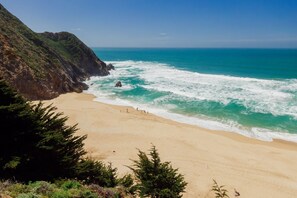 Una playa con un risco rocoso y olas del océano.