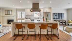 A modern kitchen with a central island, bar stools, a stainless steel range hood, and a built-in oven. - Serene Canyon Private Villa•Pool•HotTub•Sauna Retreat STR Permit Number:14614552 (Pacifica)