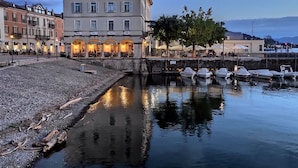 A waterfront building with multiple windows and a paved area in front. - Cosy apartment for 6 guests with A/C, WIFI, pool, TV and terrace (Luino)