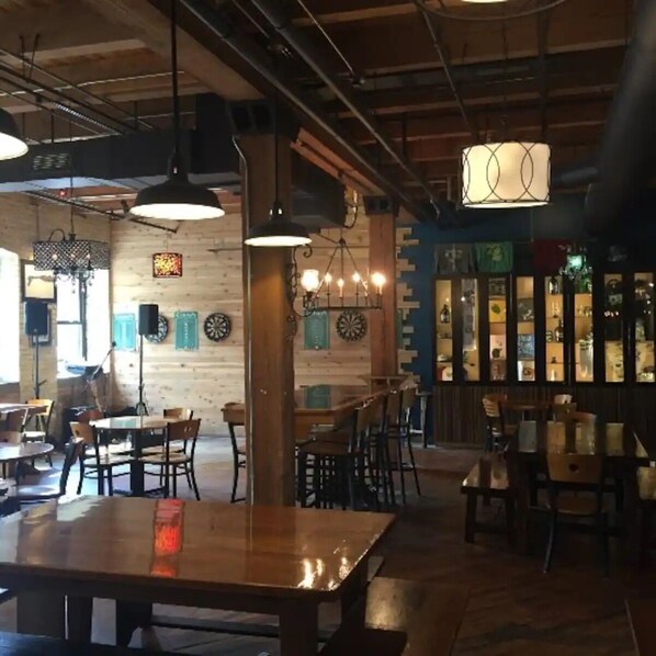 An interior with wooden walls, hanging lights, and a bar area with shelves.