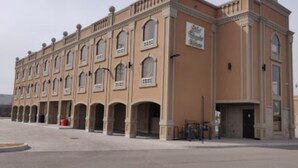 A large, historic building with a symmetrical facade, multiple arched windows, and a central entrance.