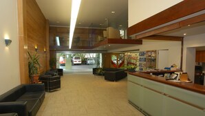 Un hall d’entrée spacieux comprenant un comptoir d’accueil, un espace salon et une vue sur les voitures garées à l’extérieur.