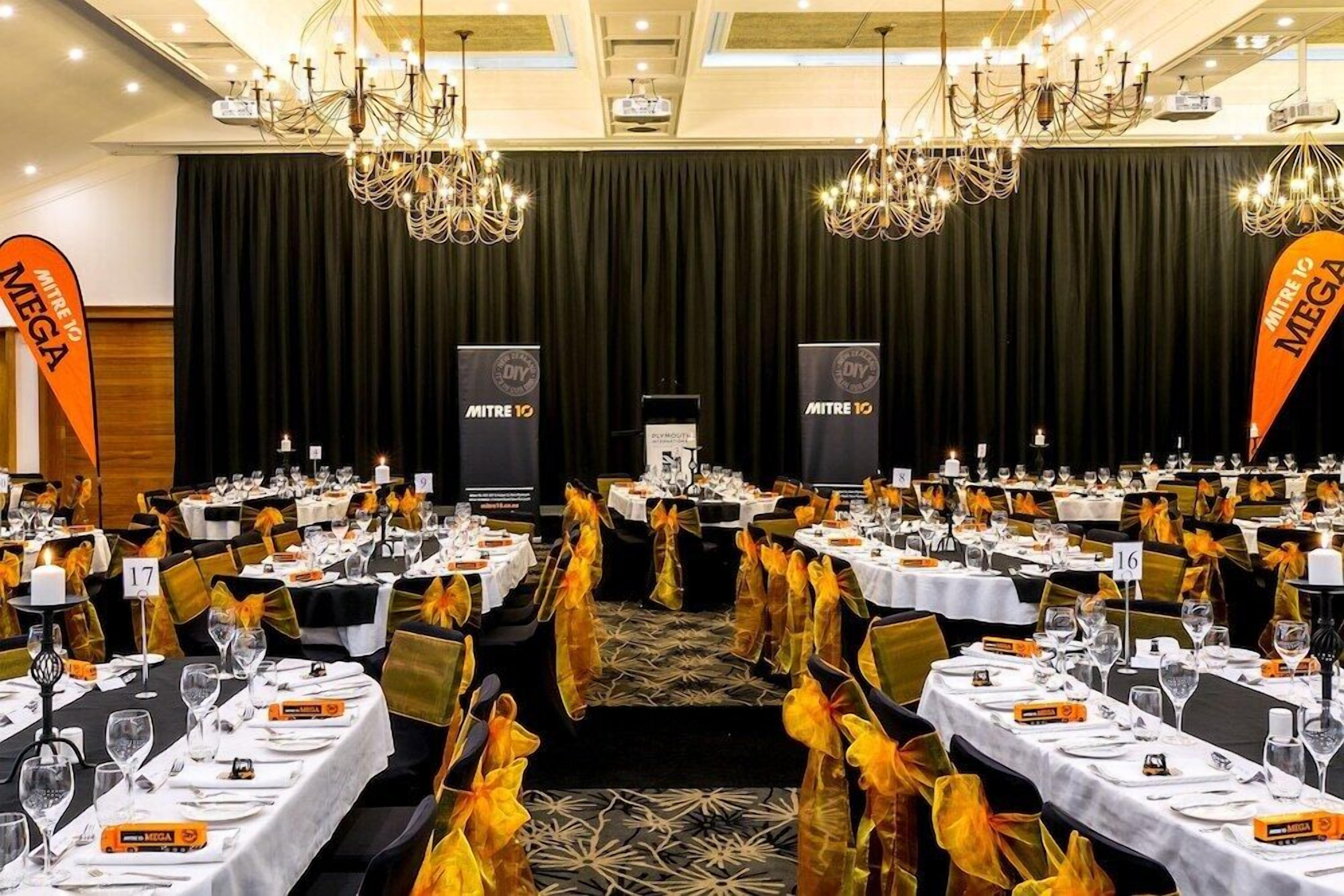 A banquet hall with rows of tables set for a formal event, each with name cards and place settings.