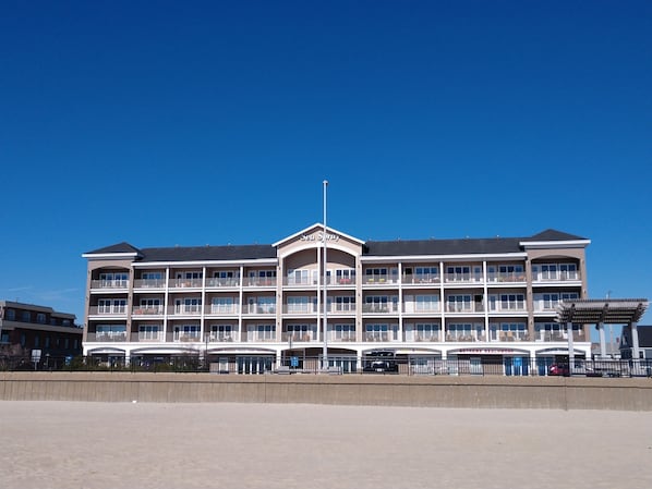 A multi-story hotel with a central atrium, balconies, and a clear sky.