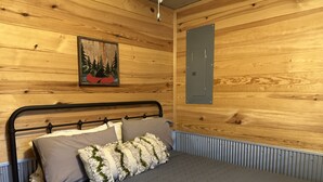 A bed with a metal frame, grey bedding, and decorative pillows.