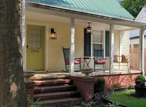 A house with a porch, a number '254' on the door, and a brick staircase leading up to it.