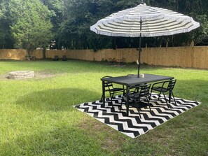 A patio area with a table and chairs, a striped umbrella, and a chevron-patterned rug.