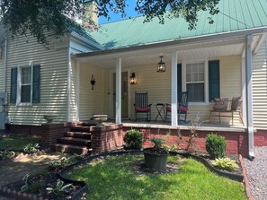 A house with a porch, two rocking chairs, a small table, and a potted plant.