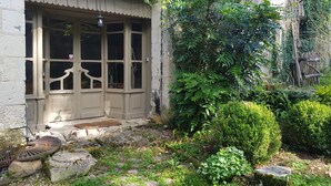 A stone building with a bay window and a small garden area with rocks and greenery.