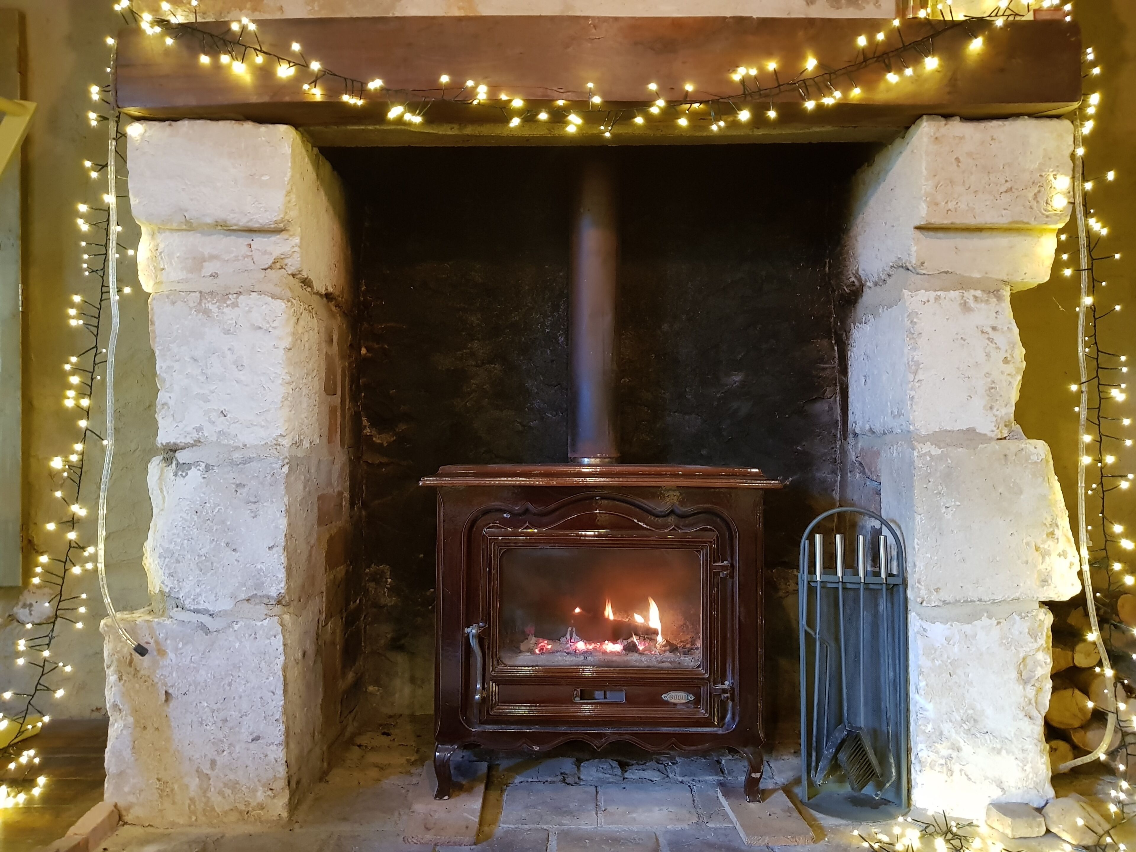 A stone fireplace with a wood-burning stove, surrounded by decorative lights.