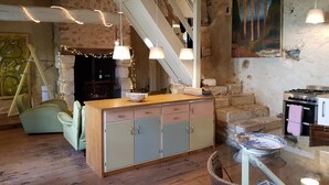 A rustic kitchen with a wooden island, stone walls, and exposed beams.