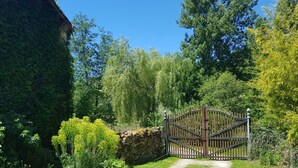A gated entrance to a property surrounded by lush greenery and a clear blue sky.