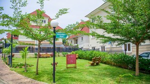 A residential area with houses, a street sign for Mekunwen Road, a lamp post, and a small garden with benches and a tree. - Furnished 4 Beds Semi-Det House in Abuja, Nigeria (Abuja)