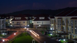 A residential street at night with houses on both sides, streetlights, and moving traffic. - Furnished 4 Beds Semi-Det House in Abuja, Nigeria (Abuja)