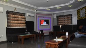 A room with a television, seating area, and bookshelves. - Beautiful 1 Bed, Living Room in a Hotel Penthouse (Awoyaya, Ibeju Lekki LG.)