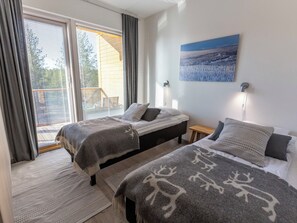 Une chambre avec deux lits, une grande fenêtre avec des stores, un tableau au mur et une petite table de chevet.