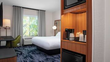 Une chambre d’hôtel équipée d’un lit, d’un bureau, d’une chaise, d’un four à micro-ondes, d’une machine à café et d’un réfrigérateur.