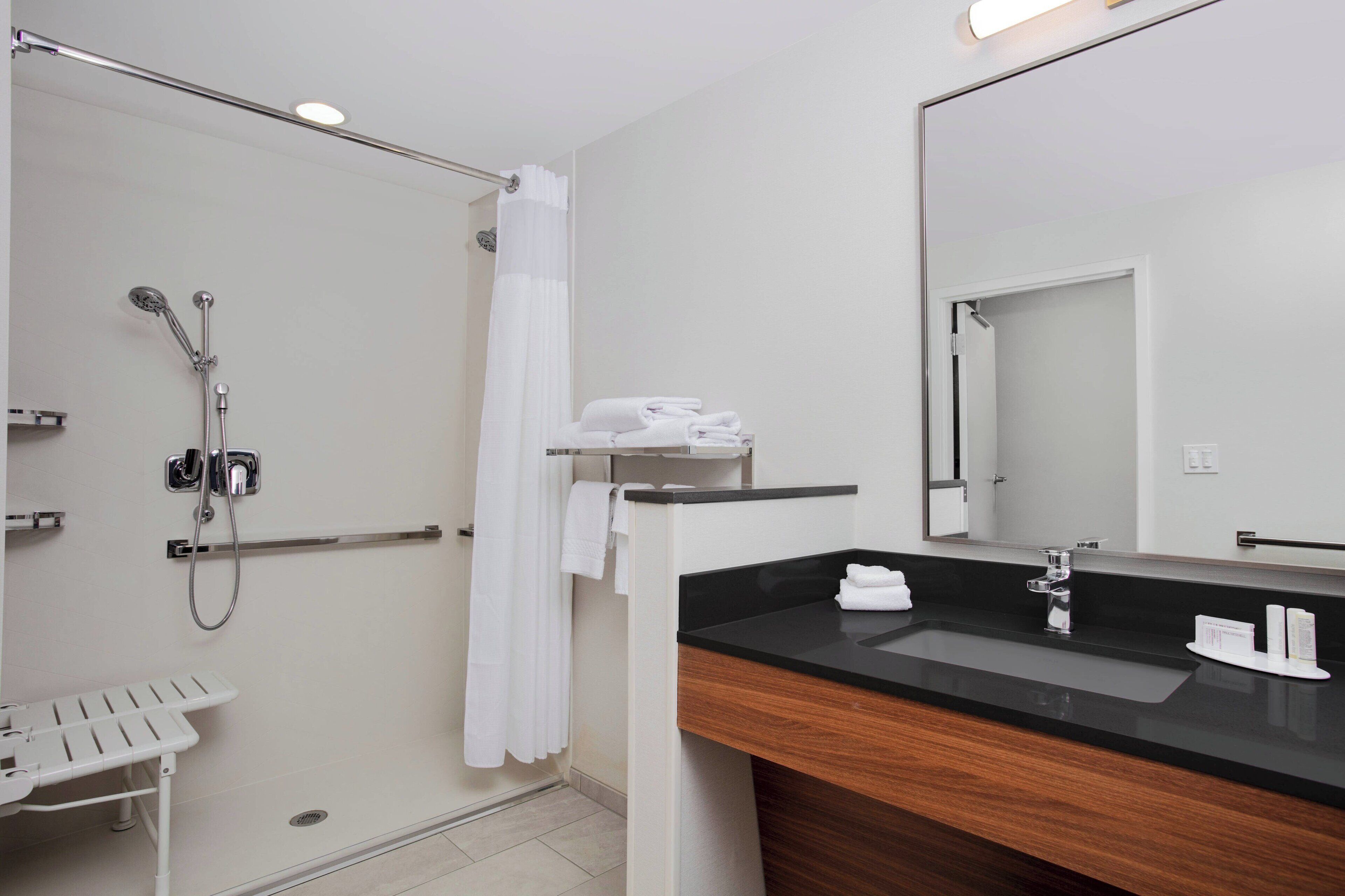 A modern bathroom with a shower, a sink, and a mirror.