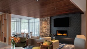 A modern living room with a stone accent wall, a fireplace, and a flat-screen TV. - Fairfield Inn & Suites by Marriott Lebanon near Expo Center (Lebanon)