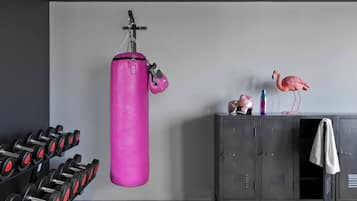 Un gimnasio con un saco de boxeo rosa, mancuernas y un armario decorado con un flamenco.