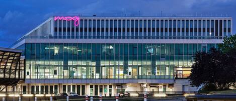 A modern building with a glass facade and a prominent pink sign.