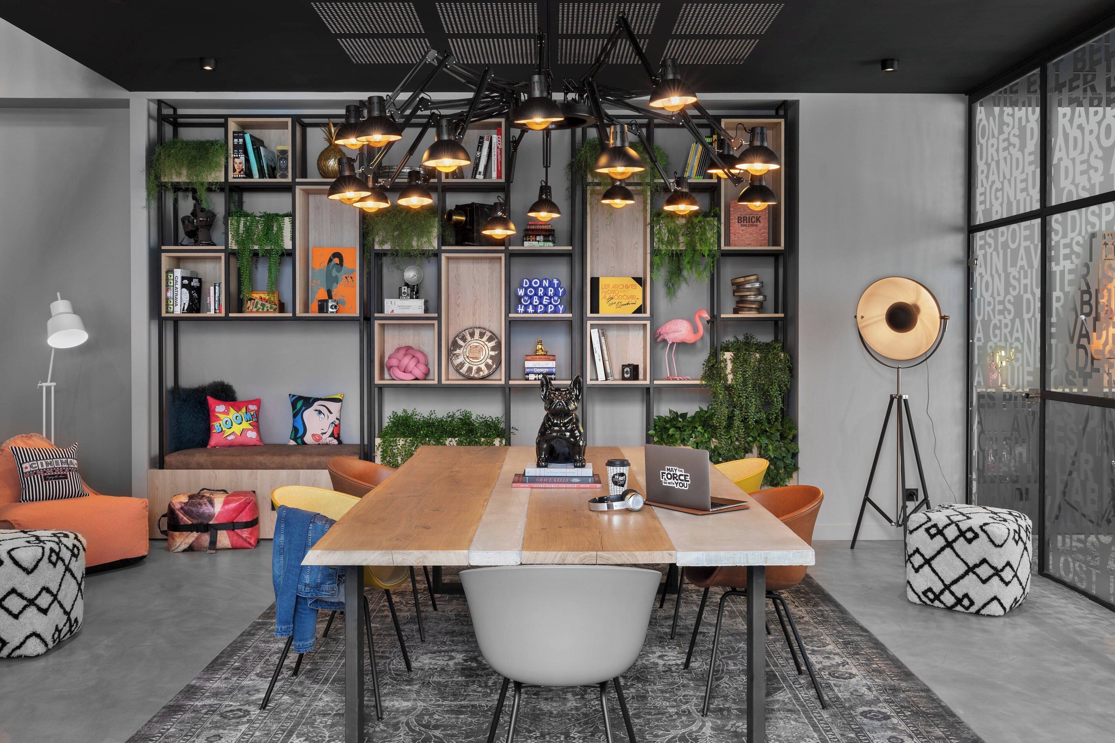 A modern living room with a wooden table, comfortable seating, a bookshelf, and decorative items.