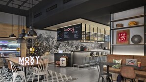 A modern bar area with a menu board, seating arrangements, and a bar counter. - Moxy Lyon Airport (Colombier-Saugnieu)