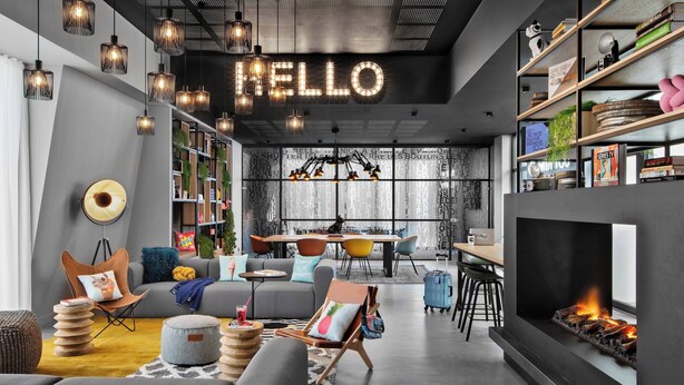 A modern living room with a fireplace, bookshelves, and a 'HELLO' sign. - Moxy Lyon Airport (Colombier-Saugnieu)