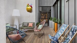 A modern outdoor seating area with various chairs and a sofa, a large potted plant, and a pineapple decoration on the wall. - Moxy Lyon Airport (Colombier-Saugnieu)