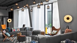 A modern living room with a grey sofa, a coffee table, and a blue suitcase. - Moxy Lyon Airport (Colombier-Saugnieu)