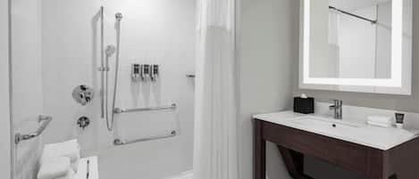 A modern bathroom with a white bathtub, shower, and vanity.