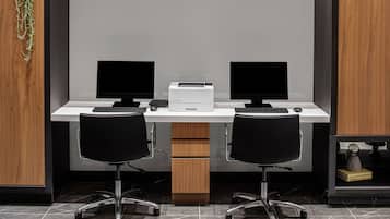 Un bureau moderne équipé de deux écrans, d’une imprimante et de deux chaises de bureau noires.