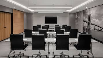 Une salle de conférence équipée d’un grand écran, de plusieurs tables et de chaises.