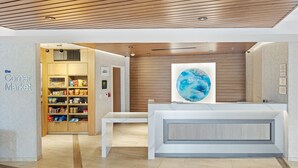 Un área de recepción moderna con techo de madera, una gran obra de arte con un globo terráqueo y una presentación de aperitivos.